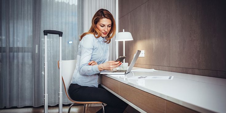 Geschäftsreisende nutzt Laptop und Smartphone im Hotelzimmer