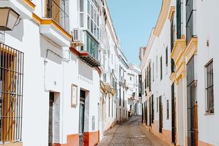 Schmale Gasse mit weißen Häuserfassaden in Andalusien