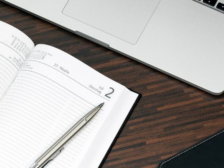 Offener Terminplaner mit Stift neben Laptop – Organisation, Planung und digitales Arbeiten im Büroalltag.
