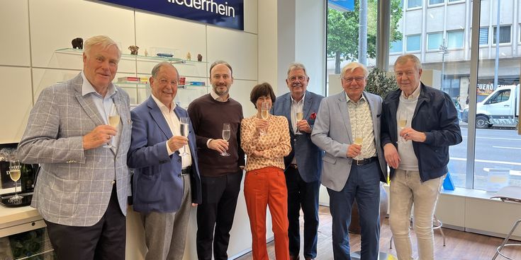 Der Verwaltungsrat und die Geschäftsführerin Frau Dr. Ute Dallmeier stoßen gemeinsam im Reisebüro auf der Bismarckstraße auf das 75-Firmenjubiläum an