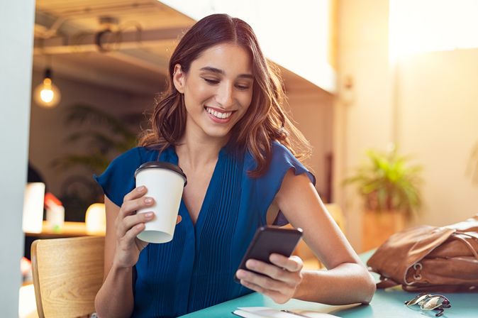 Frau mit Kaffeebecher und Handy