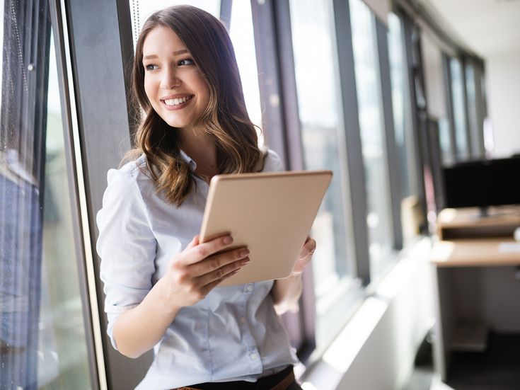 Frau mit Tablet an Fensterfront