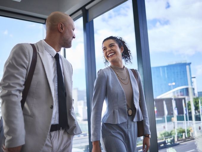 Zwei Geschäftsreisende im Gespräch auf dem Weg durch ein modernes Gebäude
