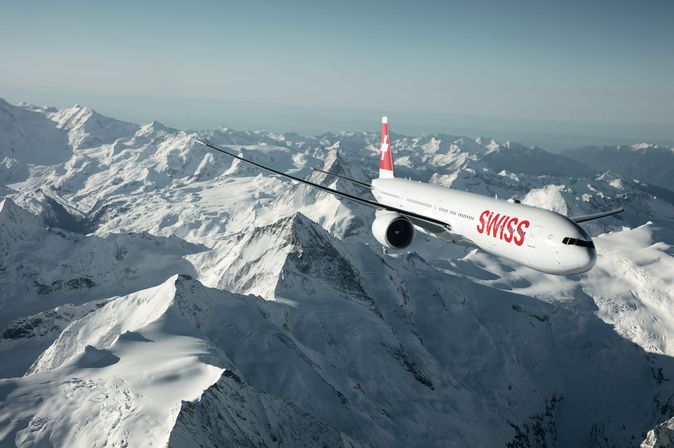 SWISS Flugzeug am Himmel über den Bergen