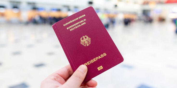 Ein Hand hält den roten Reisepass von Deutschland