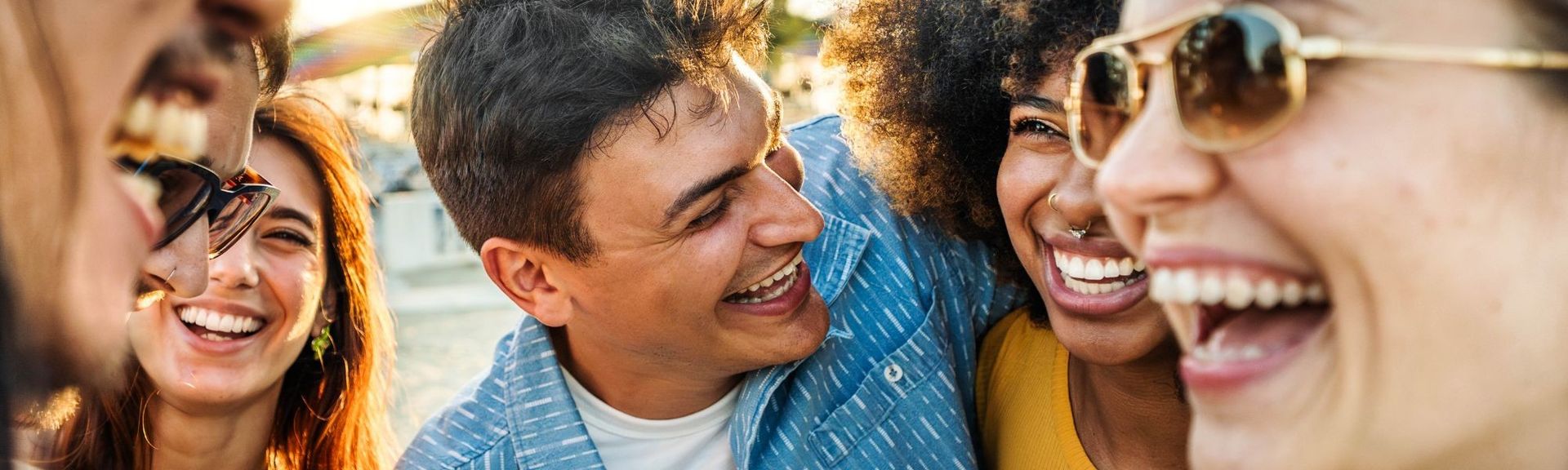 Gruppe junger Menschen lacht gemeinsam im Freien – Moment ausgelassener Freude und Gemeinschaft, der Lebensfreude und Freundschaft ausdrückt.