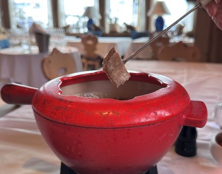 Ein roter Fonduetopf mit geschmolzenem Käse steht auf einem Tisch im Restaurant
