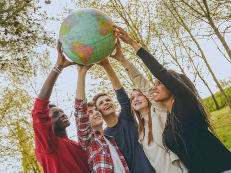 Fünf junge Menschen halten gemeinsam einen Globus in die Höhe und symbolisieren Teamgeist und Weltoffenheit.