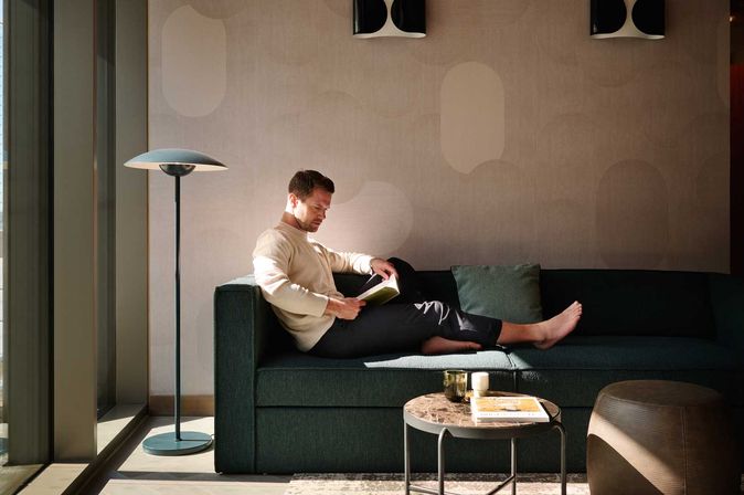 Mann liest entspannt ein Magazin auf der Couch in einem Hotel-Apartment