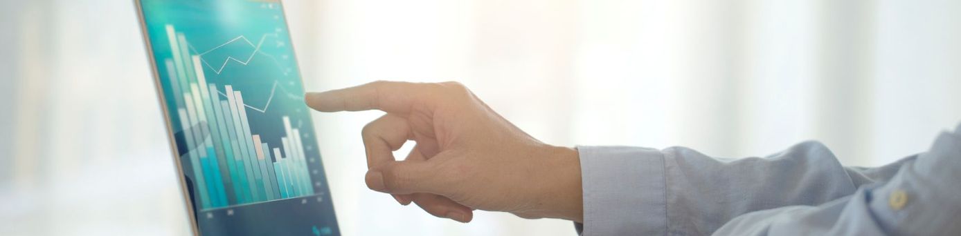 Männerhand deutet auf einen Laptop-Bildschirm, der ein Chart mit Balkendiagrammen zeigt