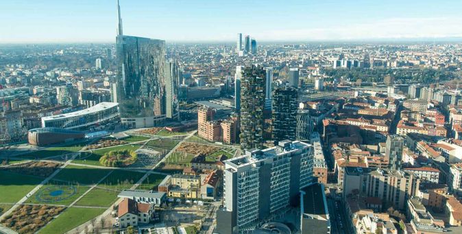 Luftaufnahme von Mailand mit Hochhäusern, Park und Stadtpanorama bei klarem Himmel.