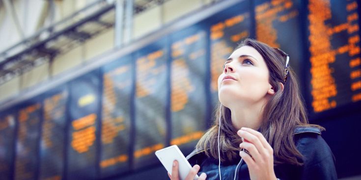 Junge Frau steht am Flughafen und blickt nach oben
