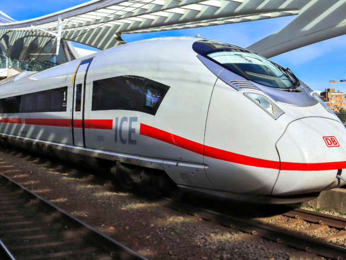 Weißer ICE 3neo-Zug der Deutschen Bahn mit rotem Streifen steht am Bahnhof unter einer modernen, geschwungenen Dachkonstruktion.