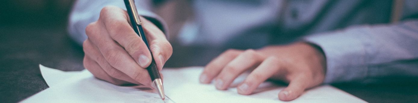 Hände eines Mannes unterschreiben ein Blatt Papier