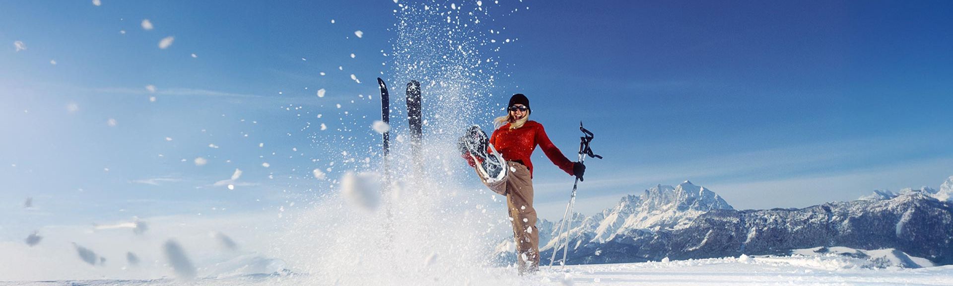 Bahn mit roter Mütze und Skistöcken schaut in die Ferne