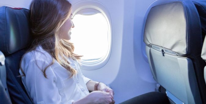 Lächelnde Frau im Flugzeug am Fenster