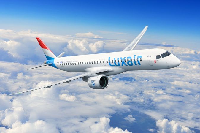 Passagierflugzeug von Luxair fliegt über den Wolken vor blauem Himmel.