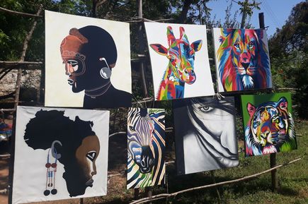 Gemälde mit Mensch- und Tiermotiven hängen auf Leine in Stadt Mombasa in Kenia