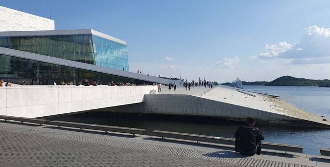 Das Opernhaus in Oslo mit seiner markanten, begehbaren Dacharchitektur und Blick auf den Fjord.