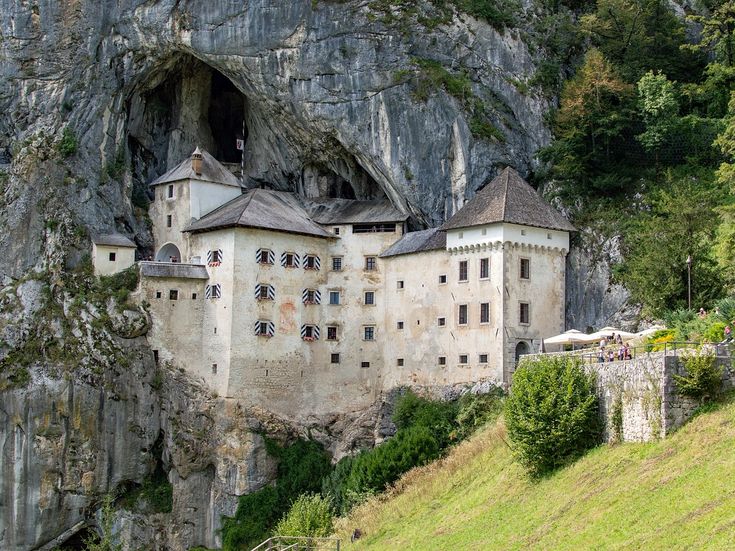 Feinsandiger Strand mit Sonnenliegen und Strohschirmen am türkisblauen Wasser bei Ksamil in Albanien, mit einer Badeplattform über dem Meer und einer grünen Insel im Hintergrund.