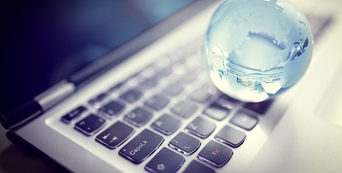 Hellblaue Weltkugel aus Glas liegt auf Tastatur