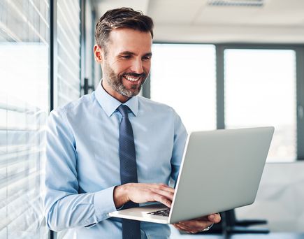 Geschäftsmann mit Laptop an Fensterfront