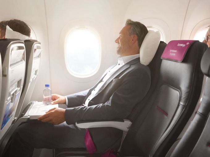 businessman lying back in his seat on board of an Eurowings flight