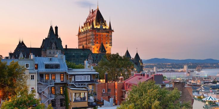 Altstadt von Québec bei Sonnenuntergang mit dem Château Frontenac im Hintergrund und bunten historischen Gebäuden im Vordergrund.