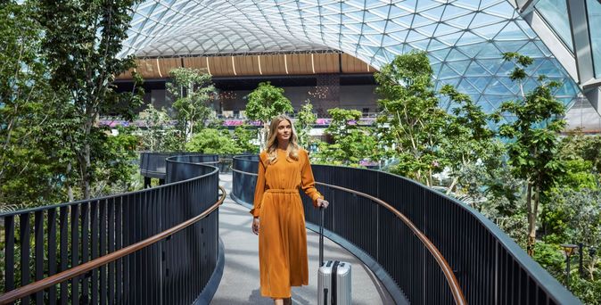 Frau mit Koffer am The Orchard Hamad International Airport © Qatar Airways