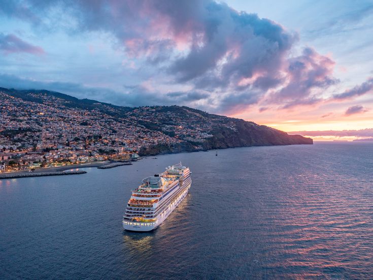 AIDAcosma vor Insel am Abend mit beleuchteten Häusern