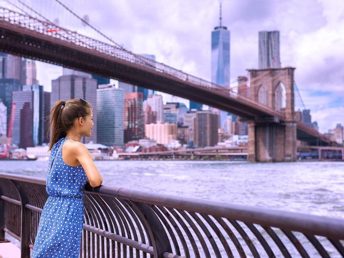 Touristin in New York schaut auf Brooklyn Bridge und Skyline