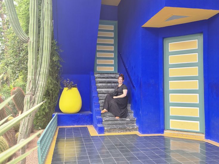 Tamara Thiemann sitzt auf einer Treppe es blau-gelb gestrichenen Hauses