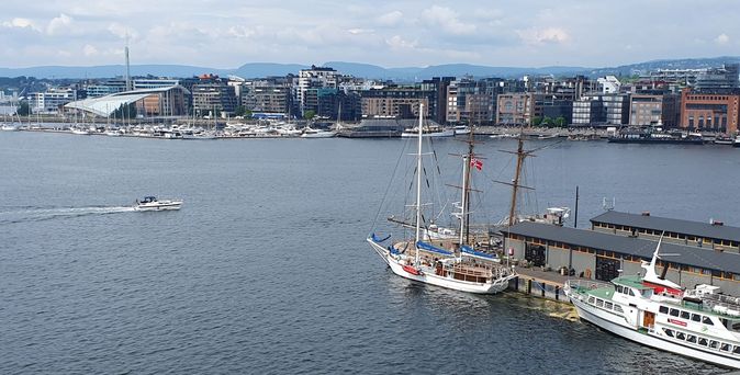 Panoramaaufnahme des Oslofjords mit Segelschiffen und der Stadt im Hintergrund.