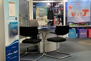 Empfangs- und Beratungsbereich eines Reisebüros mit TUI-Werbematerial und Sitzplätzen
