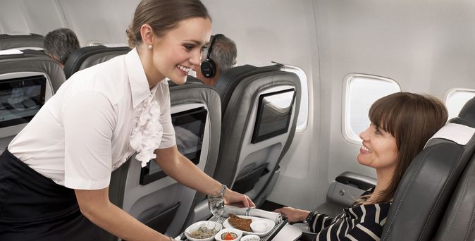 Stewardess serviert Mahlzeit für eine Passagierin in der Icelandair Saga Premium Class