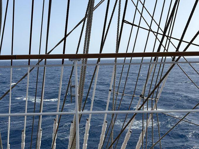Segel und Seile eines Bootes mit Blick auf das tiefblaue Mittelmeer.
