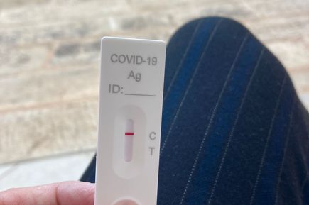 Hand hält einen Corona-Schnelltest mit negativem Ergebnis, Aufnahme im Freien