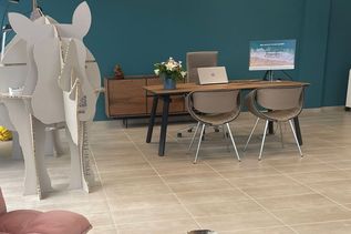 Einladender Arbeitsplatz mit Holzschreibtisch, Laptop und Blumenstrauß vor türkisfarbener Wand in der FERNWEHER Reiselounge