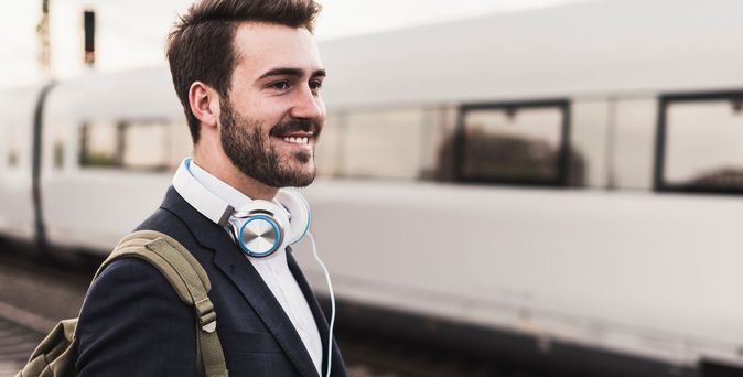 Junger Mann am Bahnsteig während ein Zug vorbeifährt