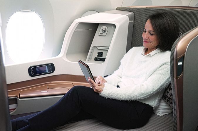 Frau entspannt sich mit einem Tablet in der Business Class einer Singapore Airlines Maschine.