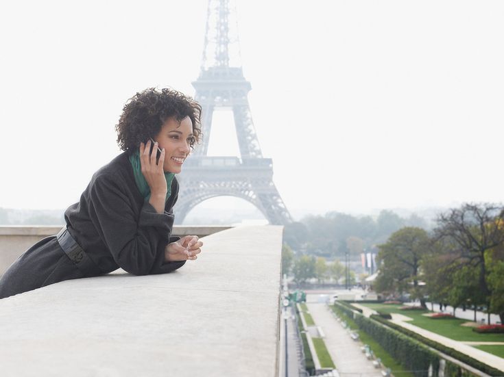 Frau mit Handy vor Eiffelturm