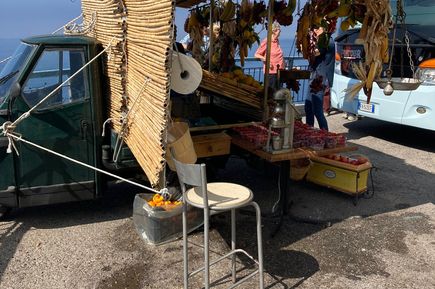 Straßenhändler mit Souvenirstand in Italien, im Hintergrund ein Reisebus und blauer Himmel.