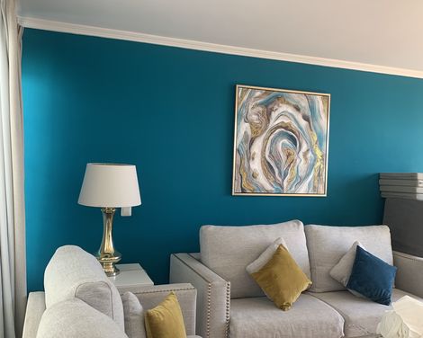 Heller Wohnbereich mit grauen Sofas, farbigen Kissen und einer türkisfarbenen Akzentwand.