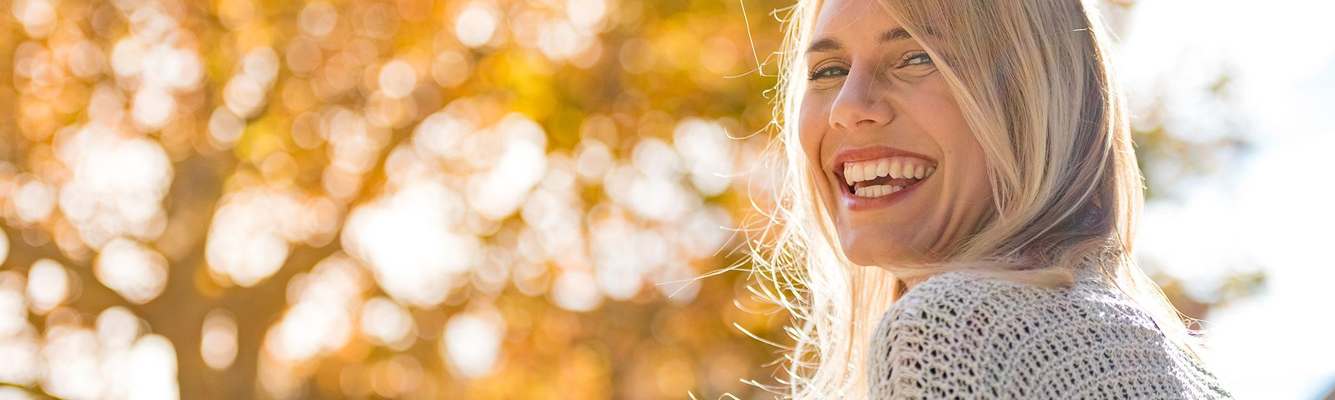 Lachende Frau vor gelbem Herbstbaum