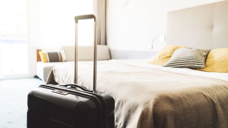 Koffer steht vorm Bett im Hotelzimmer