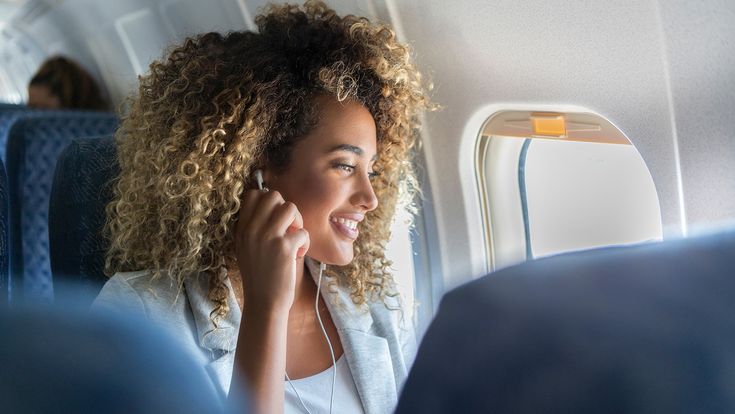 Frau mit Ohrsteckern im Flugzeug
