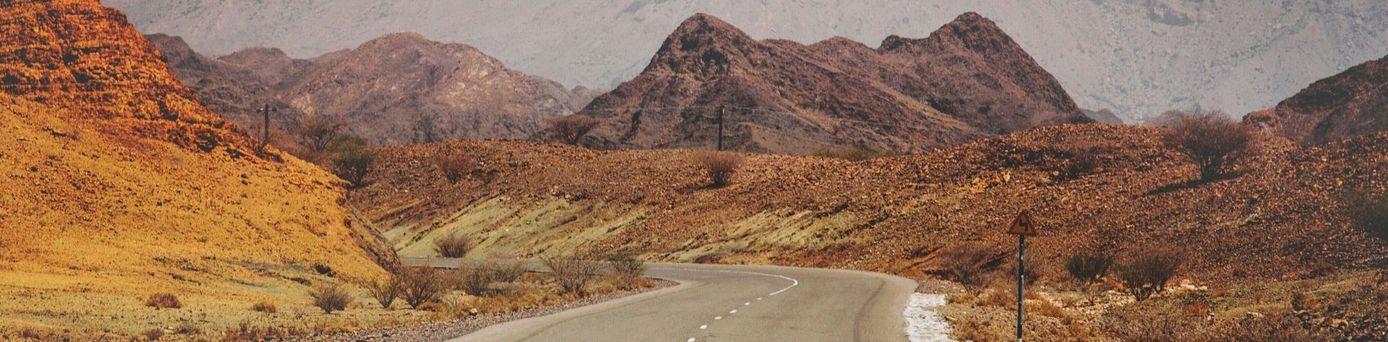 leere Straße vor Bergen im Oman