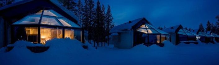 Nordlichter über schneebedeckten Glasiglus im Wald bei Nacht