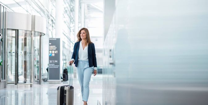 Frau mit Koffer lächelt am Flughafen