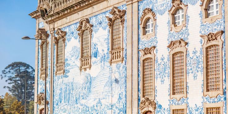 Historische Gebäudefassade in Porto mit kunstvollen blau-weißen Azulejo-Fliesen und verzierten Fenstern.
